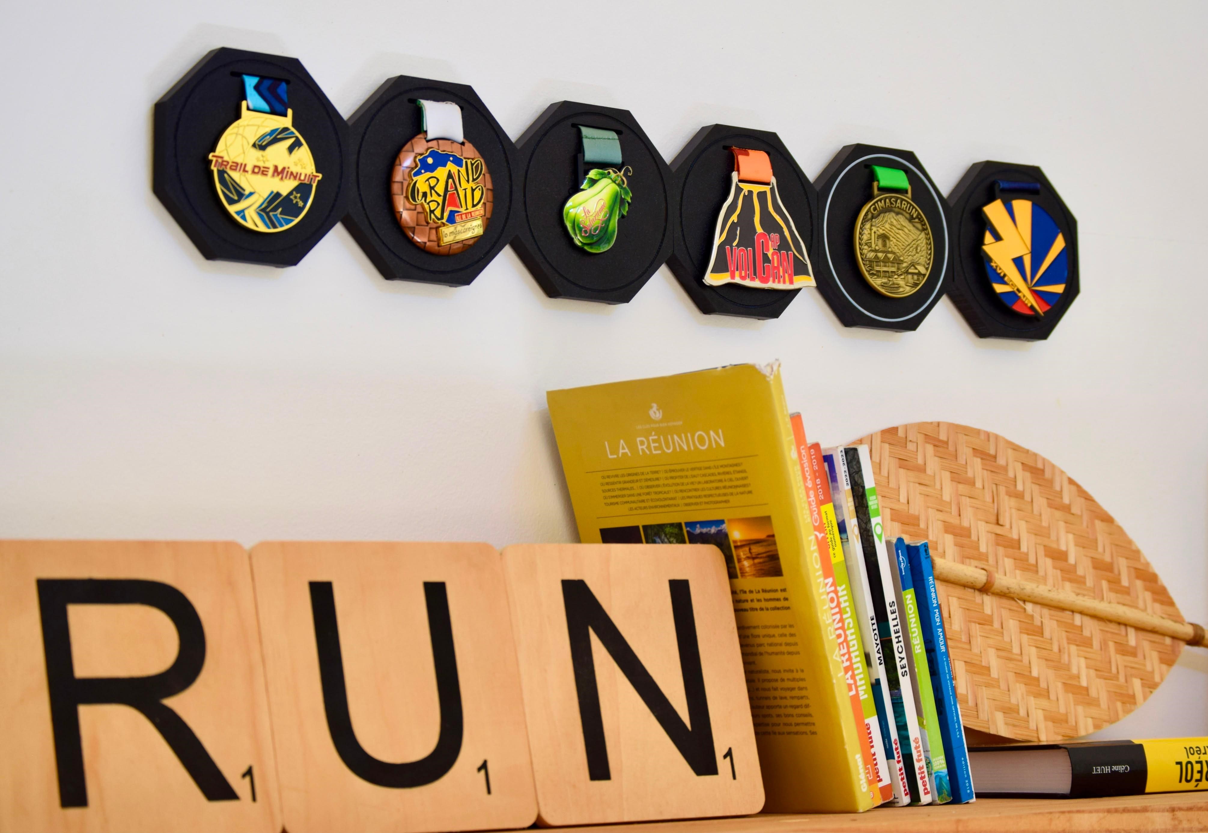 Modules SUMO alignés au mur, garnis de médailles, au-dessus des lettres RUN